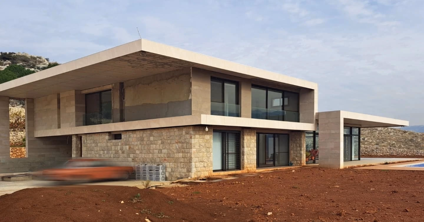 A stone and glass villa under a cantilevered roof