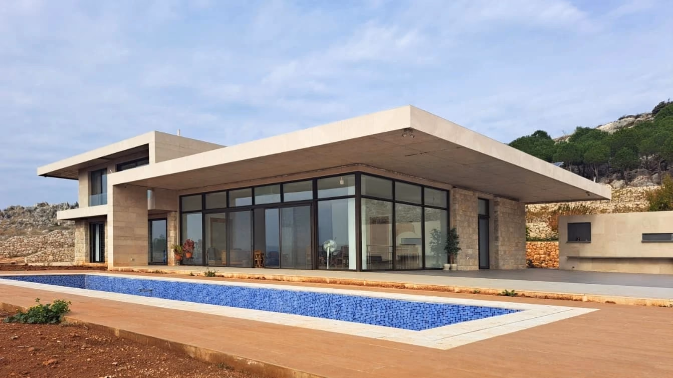 Villa with a deep flat roof over glazed rooms, beside a long pool