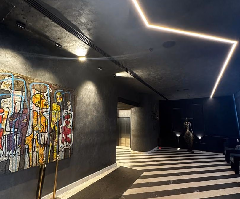 Dark corridor with angled linear lighting and artwork