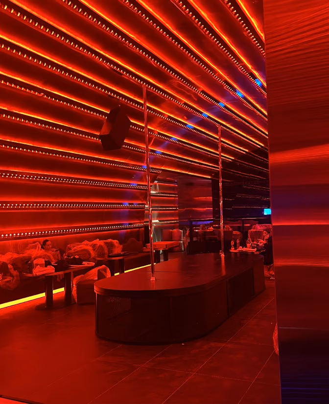 Red light lines along a wall, over seating and a raised platform