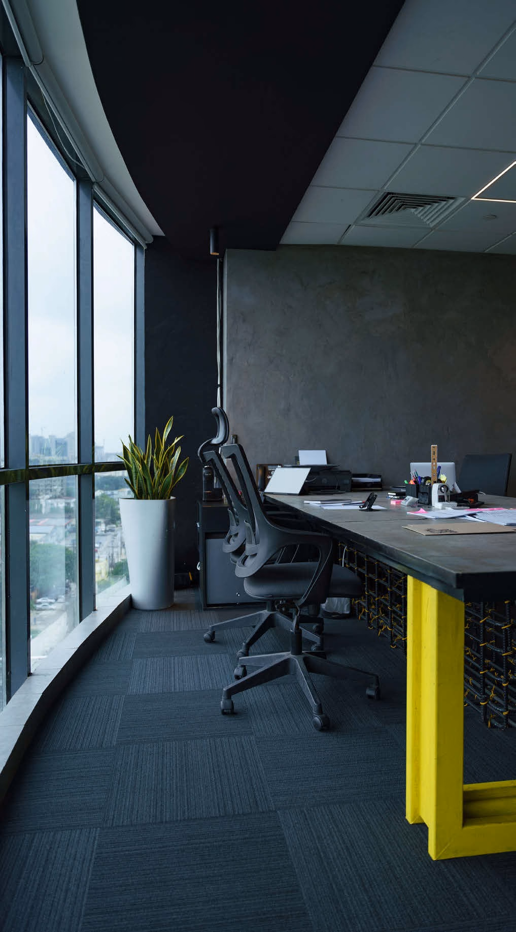 Office with a long desk beside floor-to-ceiling windows